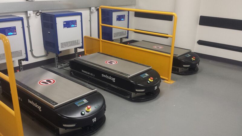 Three AGVs at charging stations in a warehouse