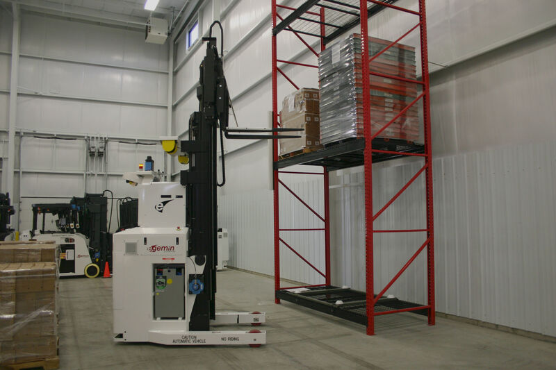 Forklift AGV with straddle picking a pallet from a rack